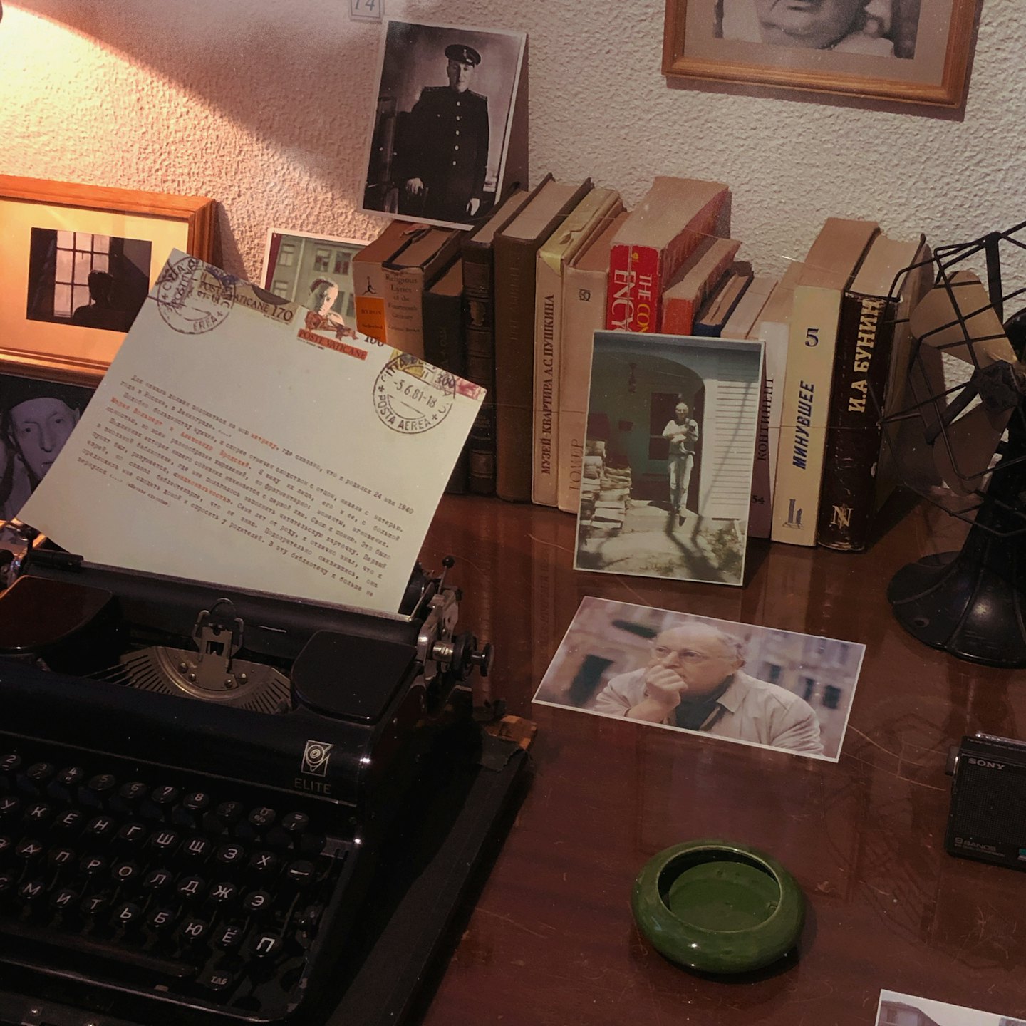 Manual typewriter sits on a desk surrounded by old books.